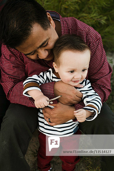 Vater umarmt lächelnden kleinen Jungen