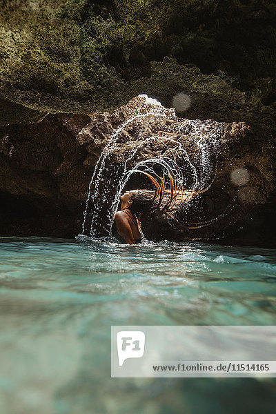 Frau in wassergefüllter Höhle  die nasses Haar zurückwirft  spritzend  Oahu  Hawaii  USA