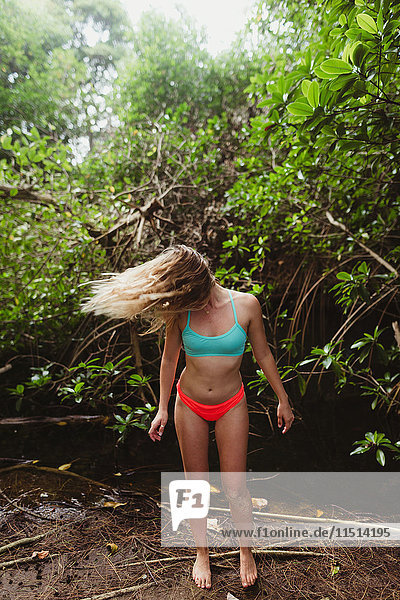 Junge Frau mit Bikini im Wald  die ihre Haare zurückwirft  Oahu  Hawaii  USA