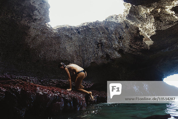 Junge Frau klettert auf Felsen  Mermaid Caves  Oahu  Hawaii  USA