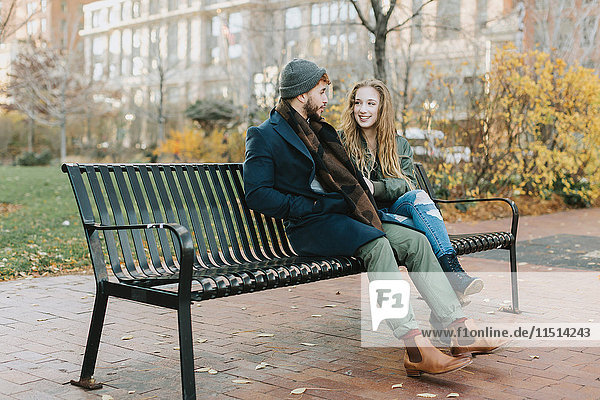 Young couple resting on park bench, Boston, Massachusetts, USA