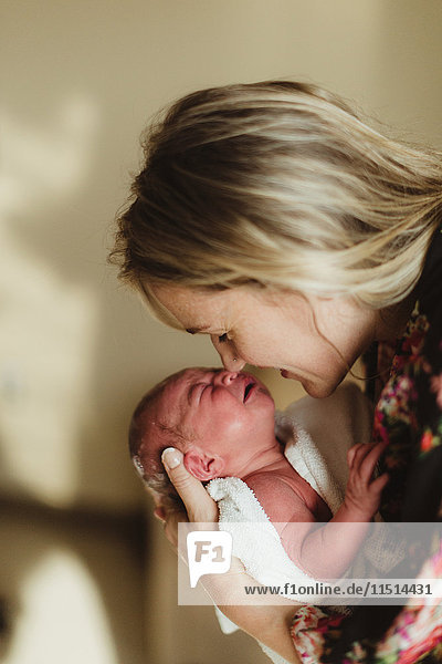 Mittlere erwachsene Frau Nase an Nase mit neugeborener Tochter