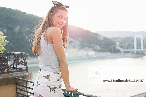 Portrait of young woman looking back on waterfront roof terrace  Budapest  Hungary