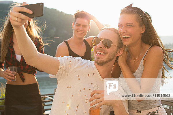 Young man taking selfie with female friend at waterfront roof terrace party  Budapest  Hungary