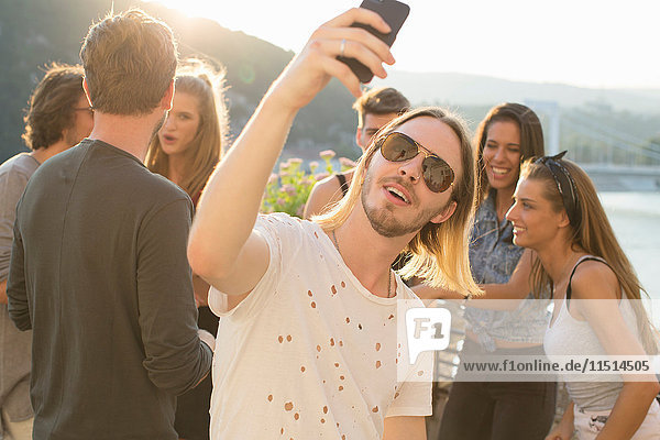 Young man taking selfie at waterfront roof terrace party  Budapest  Hungary
