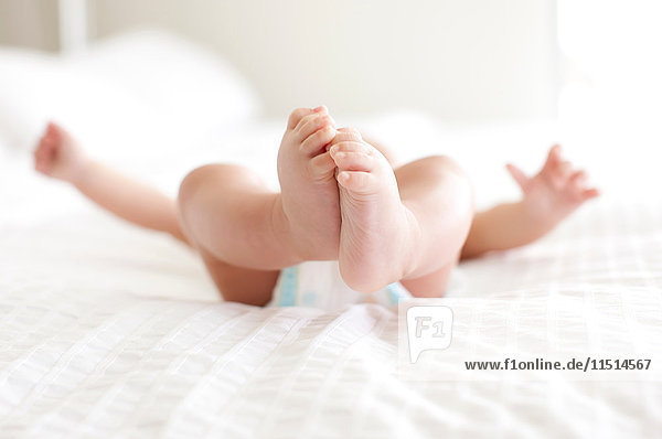 Feet of baby boy lying on his back on bed