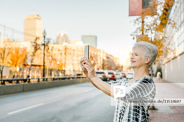 Ältere Frau im Freien  benutzt Smartphone  lächelt