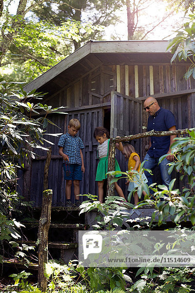 Familie steht vor einer Holzhütte