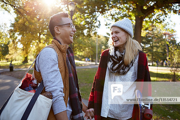 Young female skateboarder laughing with boyfriend in park