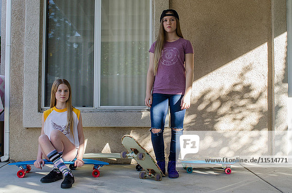 Porträt zweier jugendlicher Skateboarder-Schwestern auf der Veranda