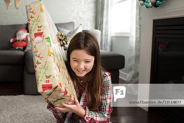 Mädchen hält lächelndes Weihnachtsgeschenk