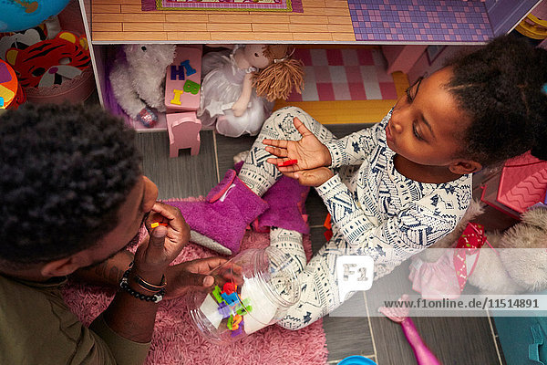 Father and daughter playing by her dolls house