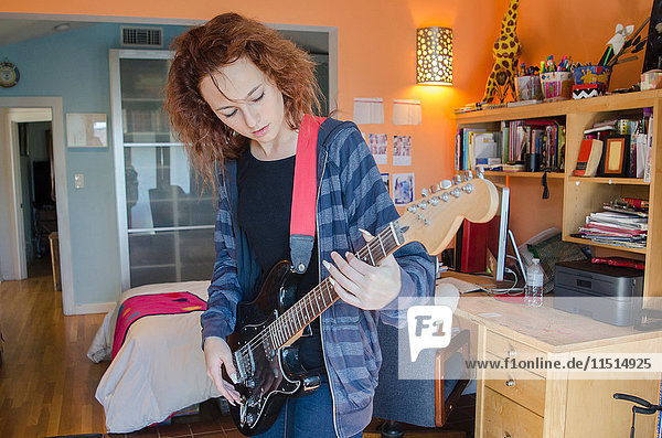Teenager spielt E-Gitarre im Schlafzimmer