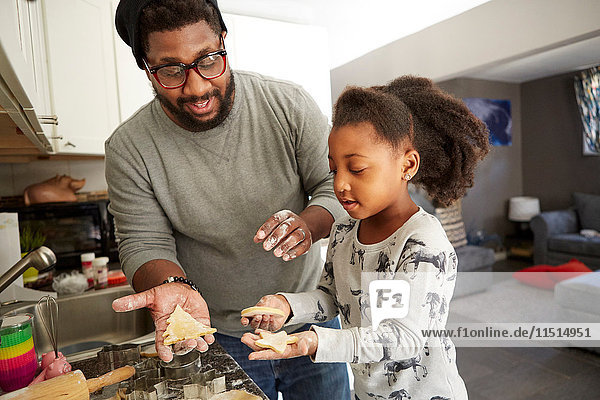 Vater und Tochter schneiden Kekse aus Keksteig