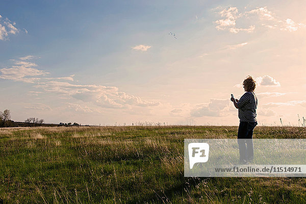 Mature woman standing in field landscape looking at smartphone near Hastings Nebraska  USA