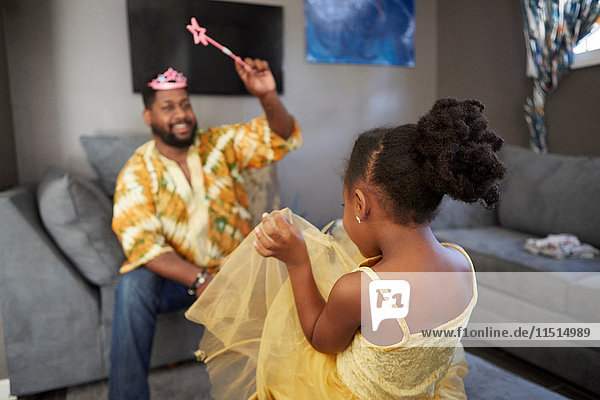 Man casting spell on daughter in fairy costume in living room