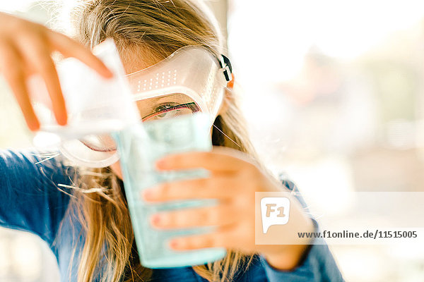 Mädchen macht wissenschaftliches Experiment  gießt Flüssigkeit ein