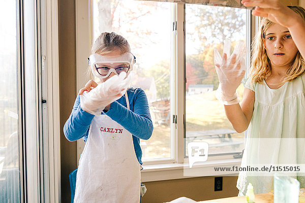 Zwei Mädchen beim wissenschaftlichen Experiment,  die große Latexhandschuhe anziehen
