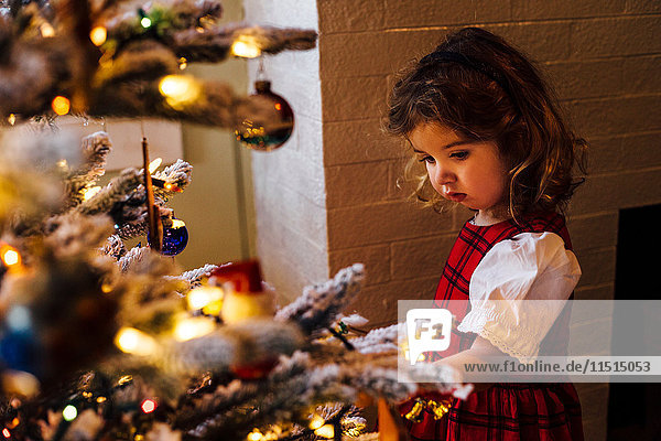 Weibliches Kleinkind starrt auf Weihnachtsbaum