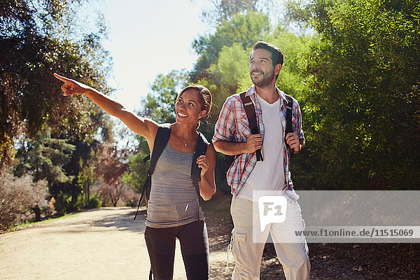 Mid adult couple hiking  pointing from sunlit rural road