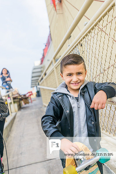 Porträt eines süßen Jungen mit Skateboards  die an ein städtisches Geländer gelehnt sind