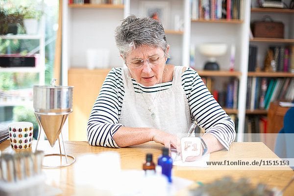 Senior woman sitting at kitchen table  writing on notepad