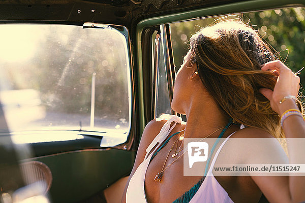 Young woman on road trip looking over her shoulder from parked truck