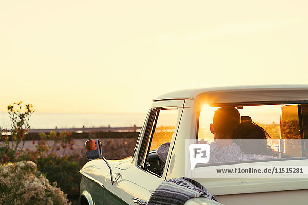 Rear view of couple in pickup truck watching sunset at Newport Beach  California  USA