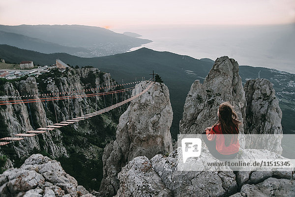 Kaukasische Frau sitzt auf einem Berg in der Nähe einer Fußgängerbrücke