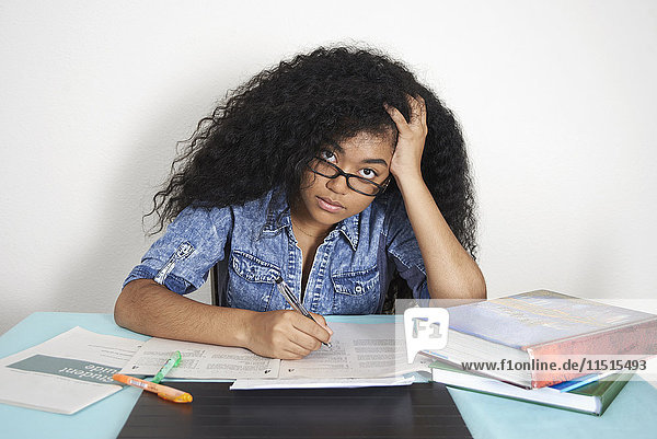 Frustrierte gemischtrassige Teenagerin macht Hausaufgaben
