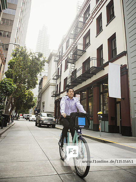 Chinesischer Geschäftsmann beim Pendeln mit dem Fahrrad in der Stadt