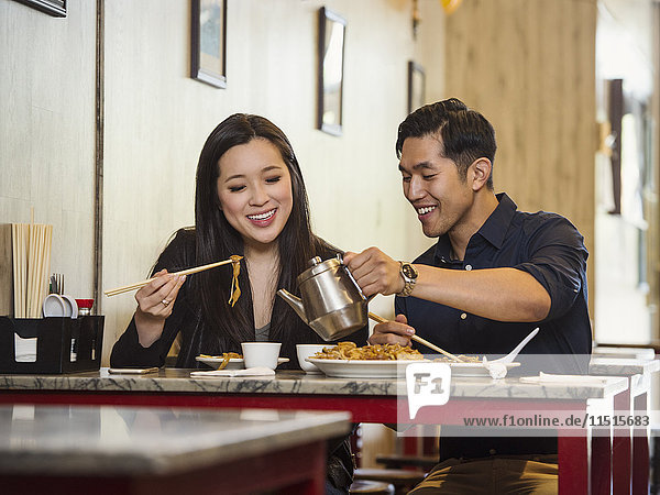 Chinesischer Mann schenkt einer Frau im Restaurant Tee ein