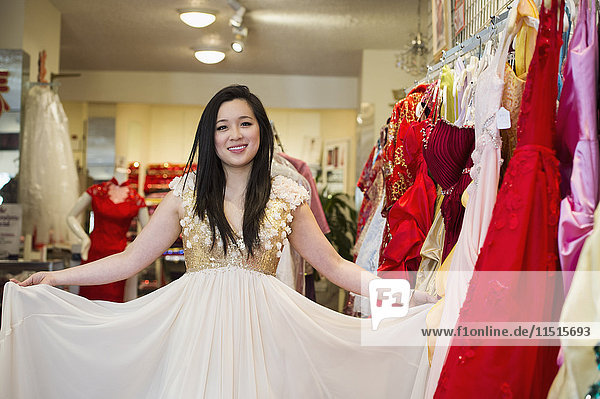 Lächelnde chinesische Frau beim Einkaufen eines Kleides
