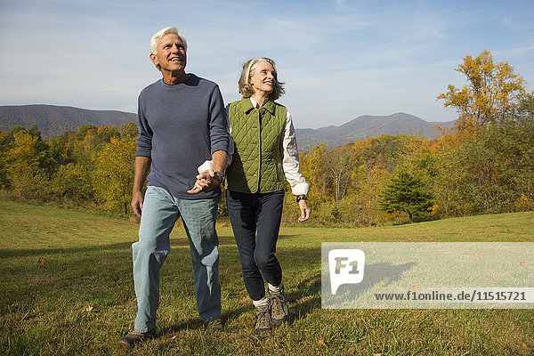 Older Caucasian couple walking in field