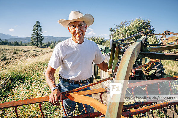 Porträt eines kaukasischen Landwirts  der neben einem Traktor steht