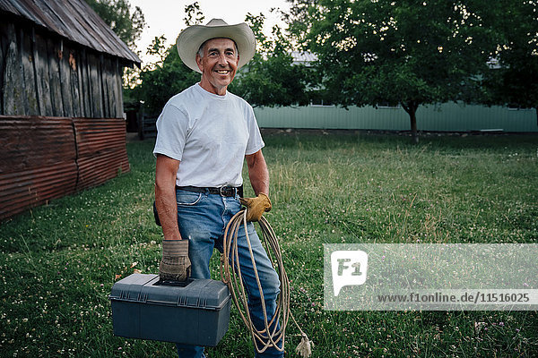 Caucasian farmer carrying rope and toolbox