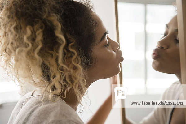 Mixed Race woman puckering lips in mirror