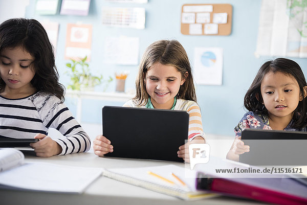 Girls using digital tablets in classroom