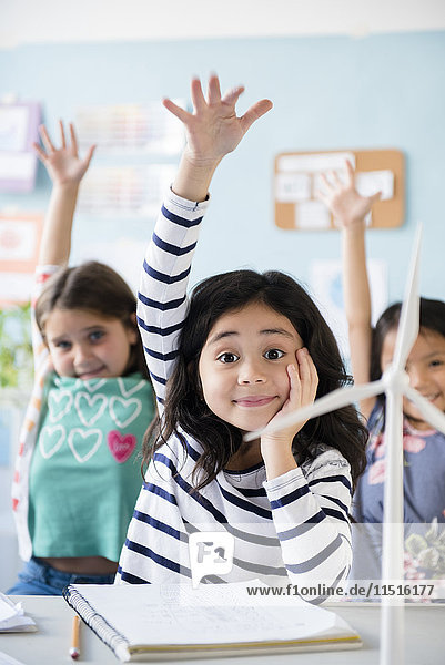 Girls learning about windmills raising hands in classroom