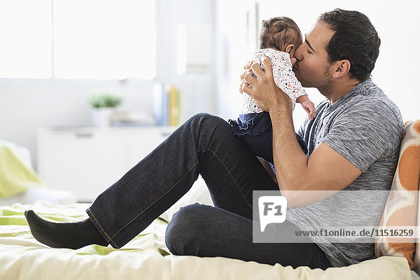 Hispanischer Vater küsst seine kleine Tochter auf die Wange