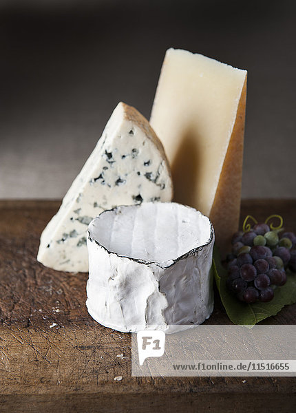 Handwerklicher Käse und Weintrauben auf einem Holztisch