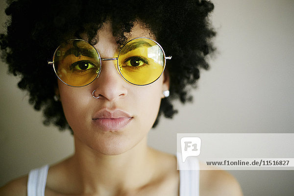 Porträt einer ernsten gemischtrassigen Frau mit gelber Sonnenbrille
