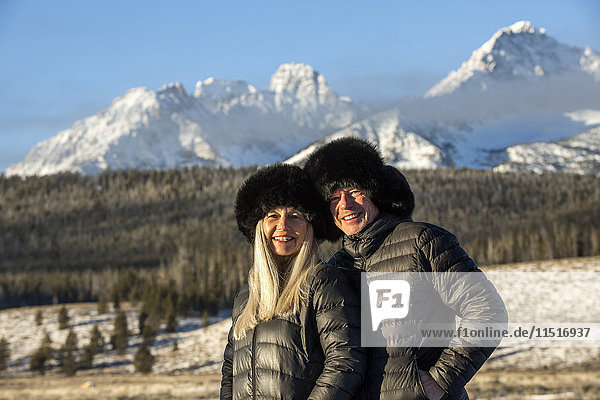 Kaukasisches Paar lächelnd in der Nähe von Bergen im Winter