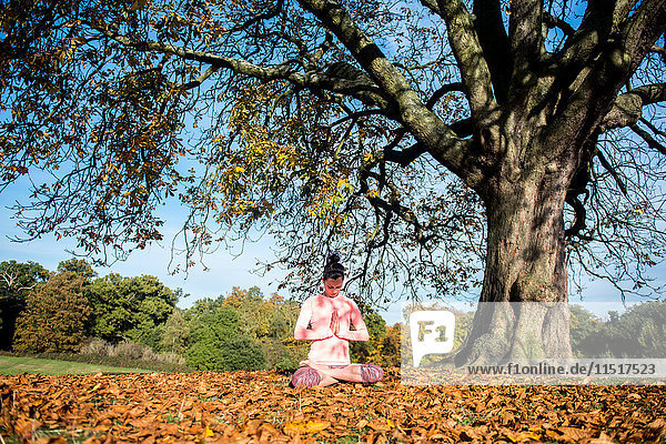 Frau macht am Herbsttag Yoga im Park