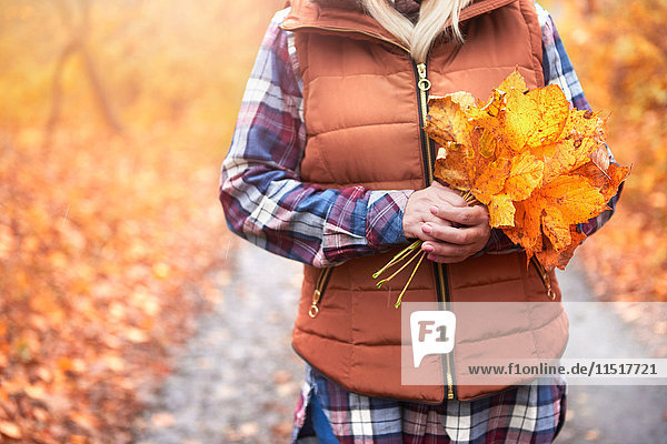 Frau im Freien stehend Herbstblätter haltend Mittelteil