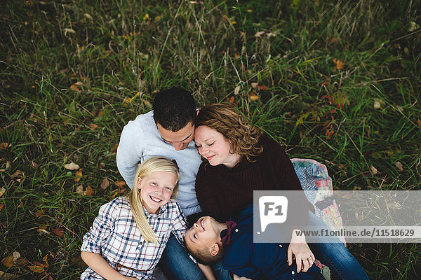 Draufsicht auf eine Familie,  die gemeinsam im Gras liegt