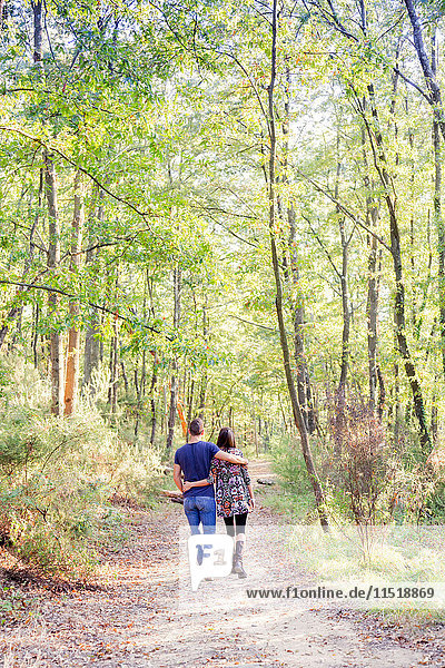 Rear view of couple walking on tree lined path