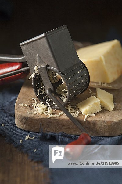 Cheddarkäse wird mit einer Vintage-Käsereibe gerieben