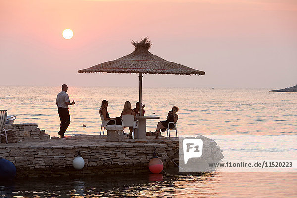 Kellner  der Touristen bei Sonnenuntergang am Küstentisch bedient  Loviste  Kroatien