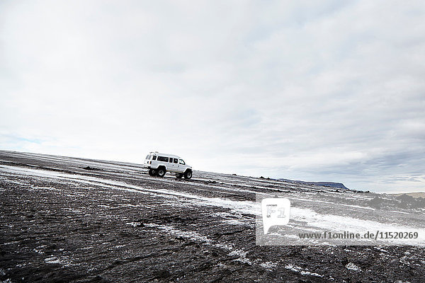 Vierrädriger Lastwagen in eisiger schwarzer Landschaft geparkt  Island
